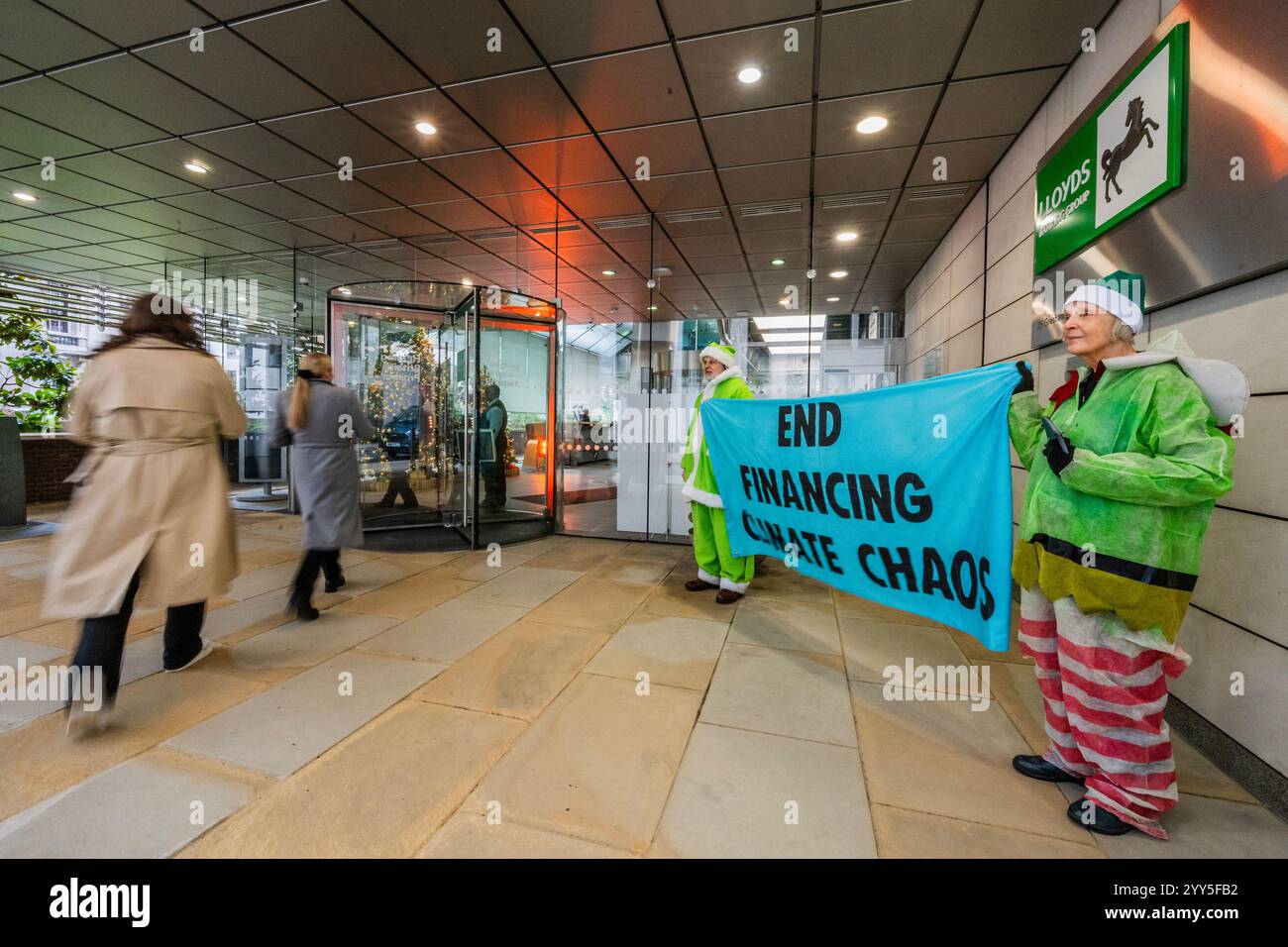 Londres, Royaume-Uni. 19 décembre 2024. Une rébellion d'extinction Green Santa et ses elfes piquèrent l'entrée principale et distribuèrent des tracts pour demander à Lloyds Bank de «nettoyer leur acte!» et pour mettre fin au financement du chaos climatique. Les manifestants pensent que Lloyds pourrait être un leader sur le climat, mais « ne prennent pas les mesures nécessaires ». La manifestation a eu lieu devant le siège de la Banque à Gresham Street, dans la ville de Londres. Crédit : Guy Bell/Alamy Live News Banque D'Images