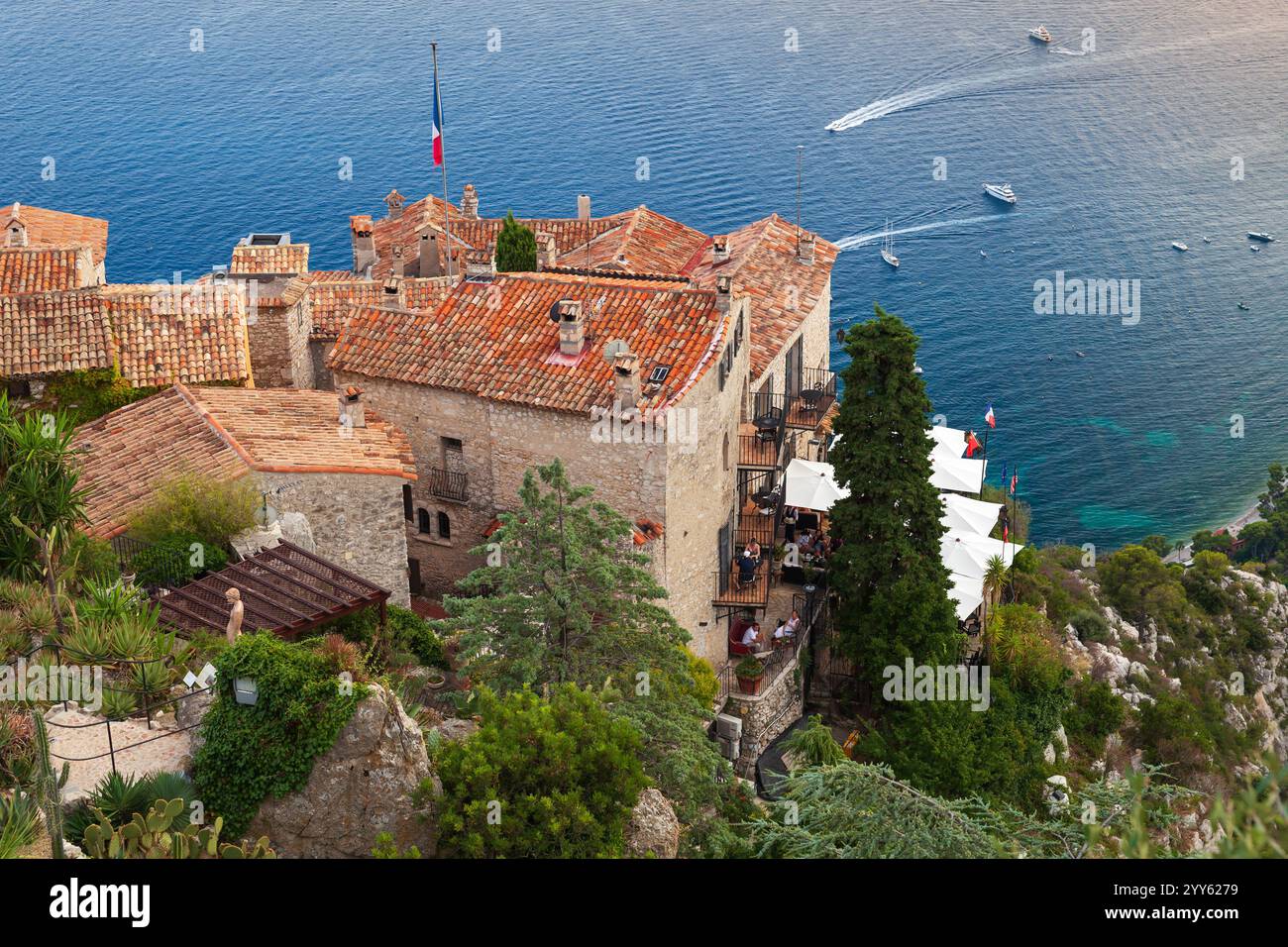 Èze, France - 15 août 2018 : paysage côtier des Alpes-Maritimes, les gens se reposent sur les balcons de la vieille maison aux toits de tuiles rouges Banque D'Images