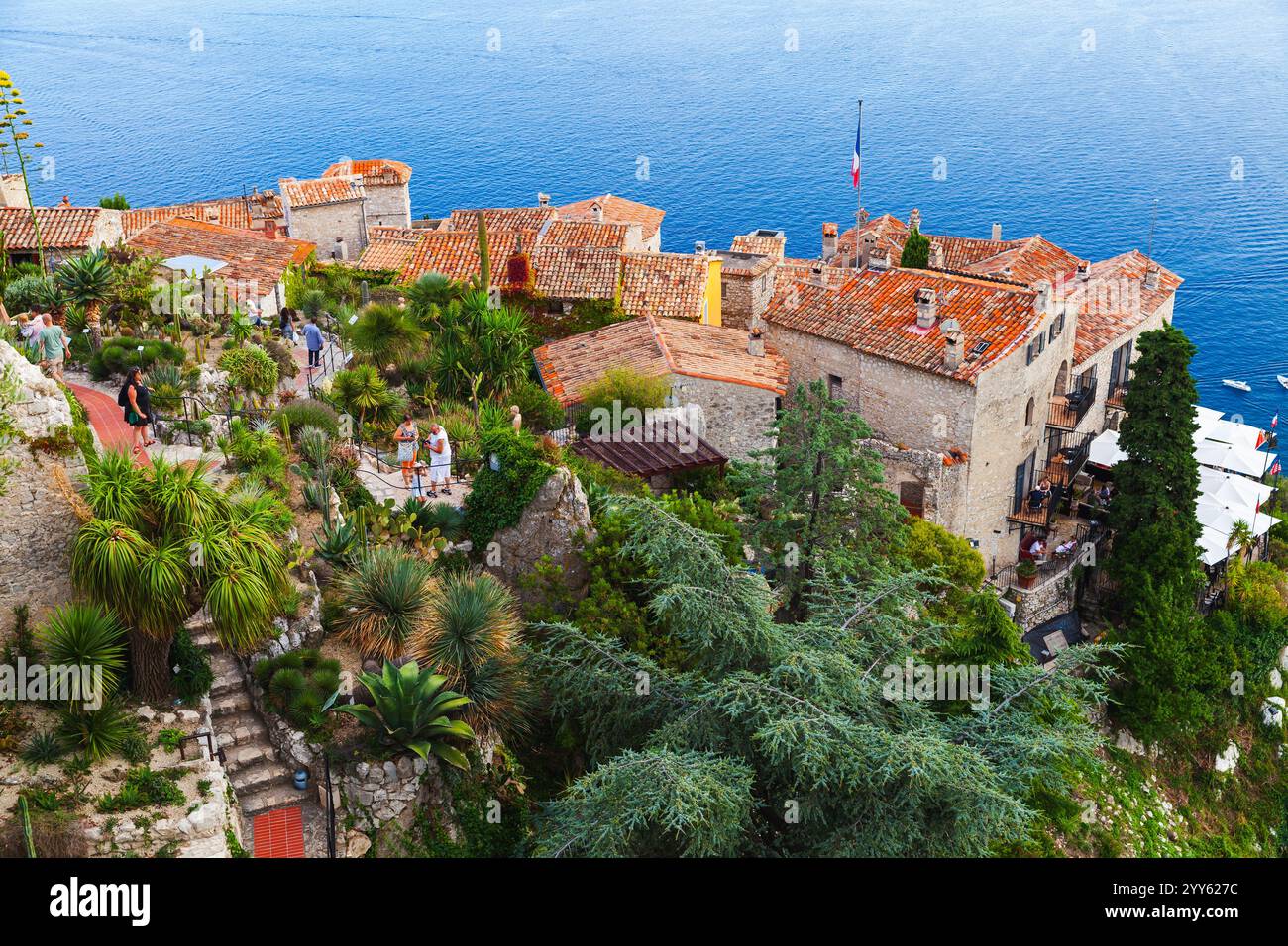 Èze, France - 15 août 2018 : paysage côtier des Alpes-Maritimes, les gens marchent dans le parc public et se reposent sur les balcons des vieilles maisons aux toits de tuiles rouges Banque D'Images