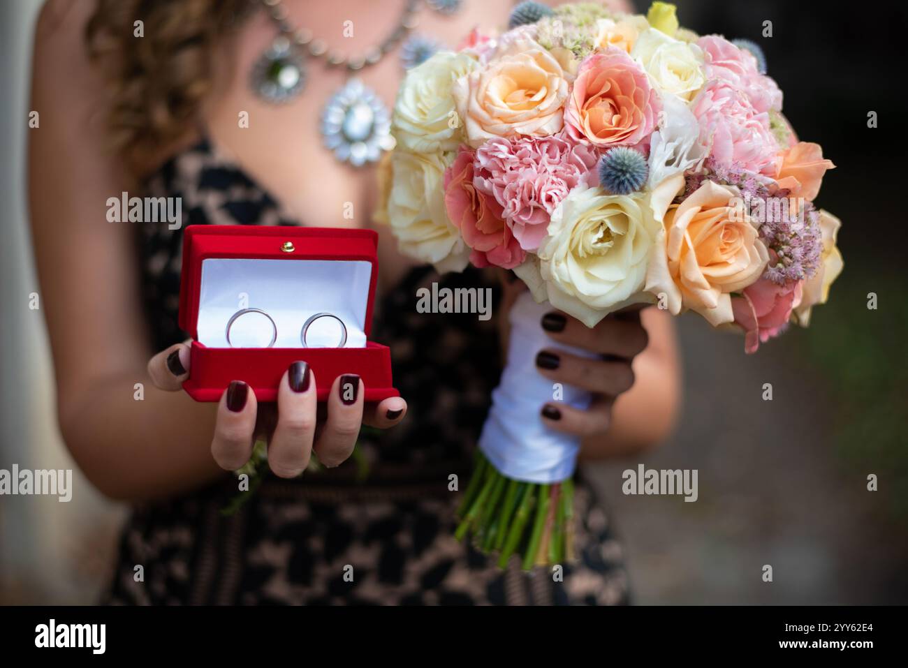 Gros plan portrait de femme tenant un beau bouquet de mariage coloré et des anneaux de mariage dans la boîte rouge Banque D'Images Gros plan portrait de femme tenant un beau bouquet de mariage coloré et des anneaux de mariage dans la boîte rouge Banque D'Images