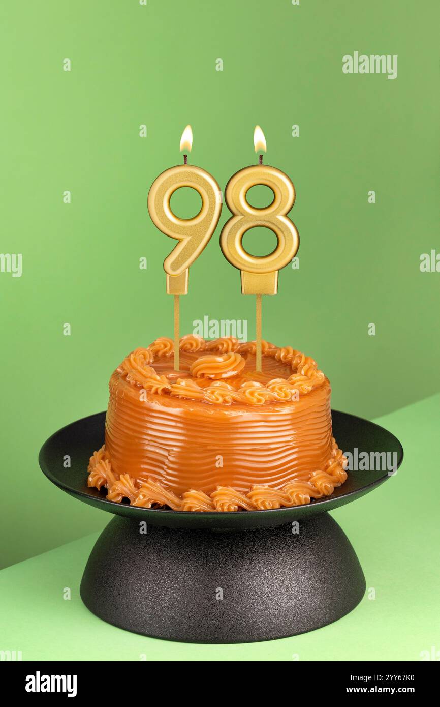 Délicieux gâteau avec dulce de leche - bougie d'anniversaire numéro 98 sur fond vert. Banque D'Images