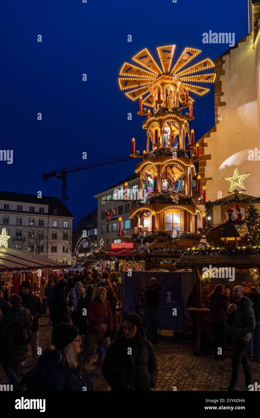 Bâle, Suisse - 5 décembre 2024 : pyramide traditionnelle du marché de Noël en soirée sur la Barfusserplatz avec des lumières festives Banque D'Images