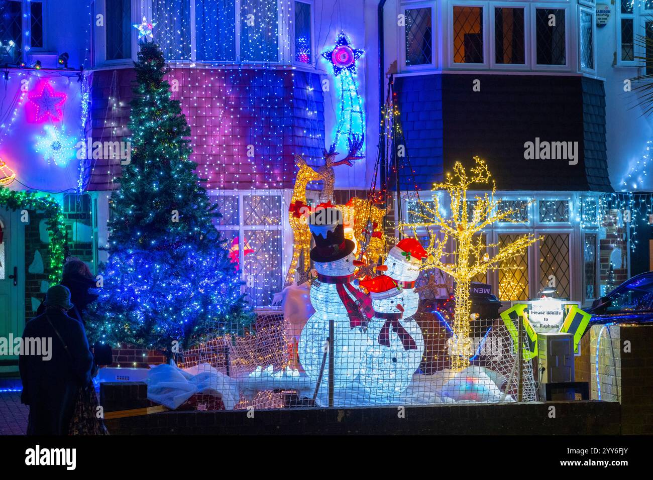 Lower Morden Lane, Surrey, Royaume-Uni. 19 décembre 2024. Les résidents de cette rue résidentielle du sud de Londres décorent l’extérieur de leur maison chaque année, amassant des fonds pour le St Raphael’s Hospice localement qui offre des soins palliatifs et de fin de vie aux habitants de Merton et Sutton. Cette année, ils ont créé une extravagance d'un quart de mile de long de lumières dans les jardins de devant, visités chaque soir par les familles qui apprécient le spectacle. Crédit : Malcolm Park/Alamy Live News Banque D'Images