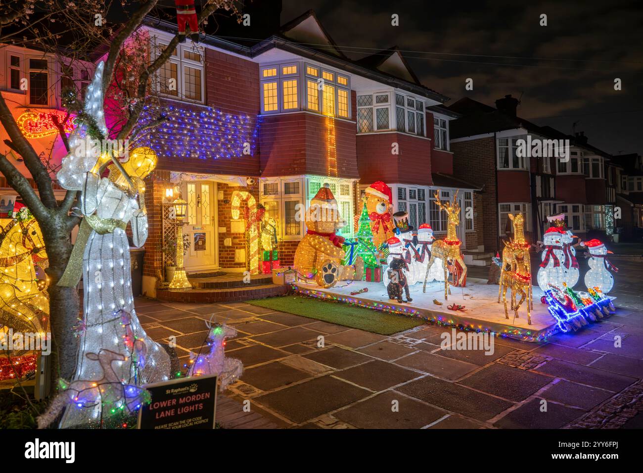 Lower Morden Lane, Surrey, Royaume-Uni. 19 décembre 2024. Les résidents de cette rue résidentielle du sud de Londres décorent l’extérieur de leur maison chaque année, amassant des fonds pour le St Raphael’s Hospice localement qui offre des soins palliatifs et de fin de vie aux habitants de Merton et Sutton. Cette année, ils ont créé une extravagance d'un quart de mile de long de lumières dans les jardins de devant, visités chaque soir par les familles qui apprécient le spectacle. Crédit : Malcolm Park/Alamy Live News Banque D'Images