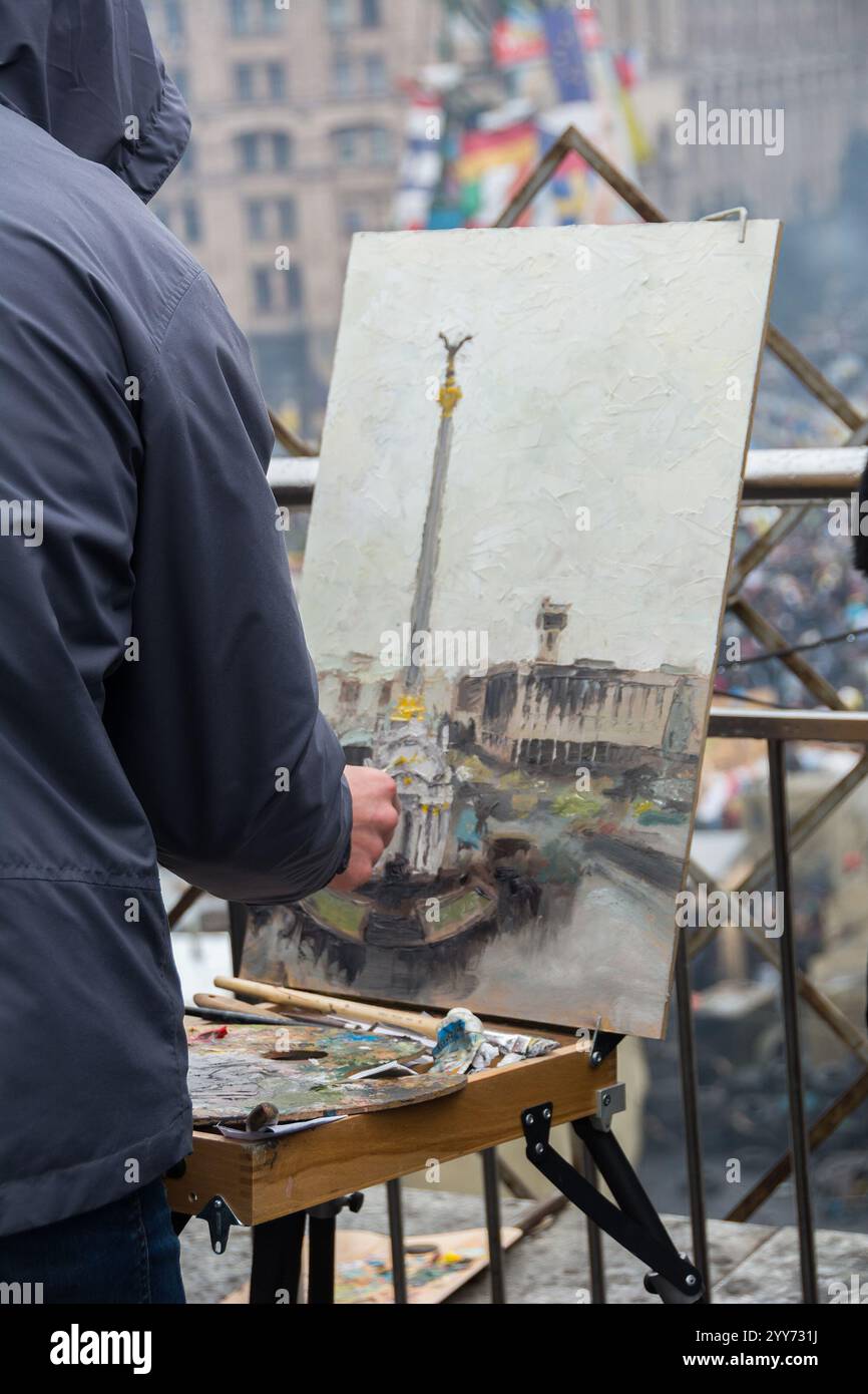 Vue au-dessus de l'épaule d'un homme peignant le Monument de l'indépendance après les événements de la Révolution de la dignité. L'artiste dessine la place Maidan Nezalezhnosti. Banque D'Images