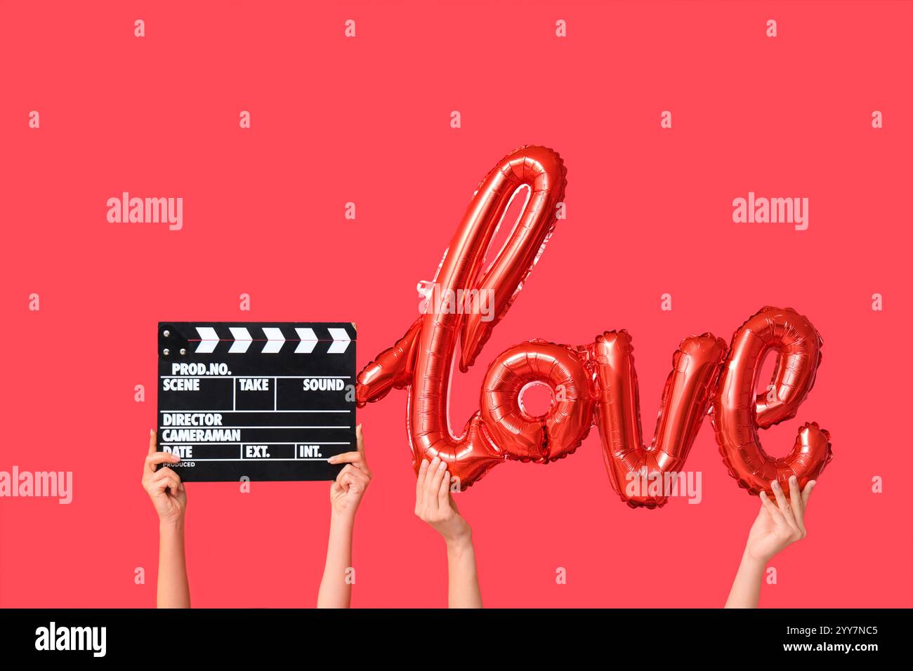Mains féminines avec ballon d'air en forme de mot AMOUR et battant de film sur fond rouge. Célébration de la Saint-Valentin Banque D'Images