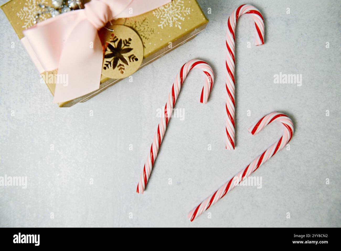 Cannes de bonbons festives et un cadeau avec un ruban rose et un flocon de neige Banque D'Images
