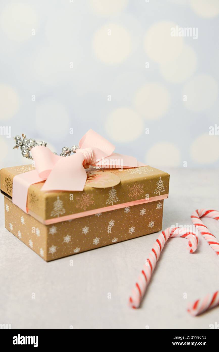 Boîte cadeau dorée avec ruban rose, décor scintillant et cannes de bonbons o Banque D'Images