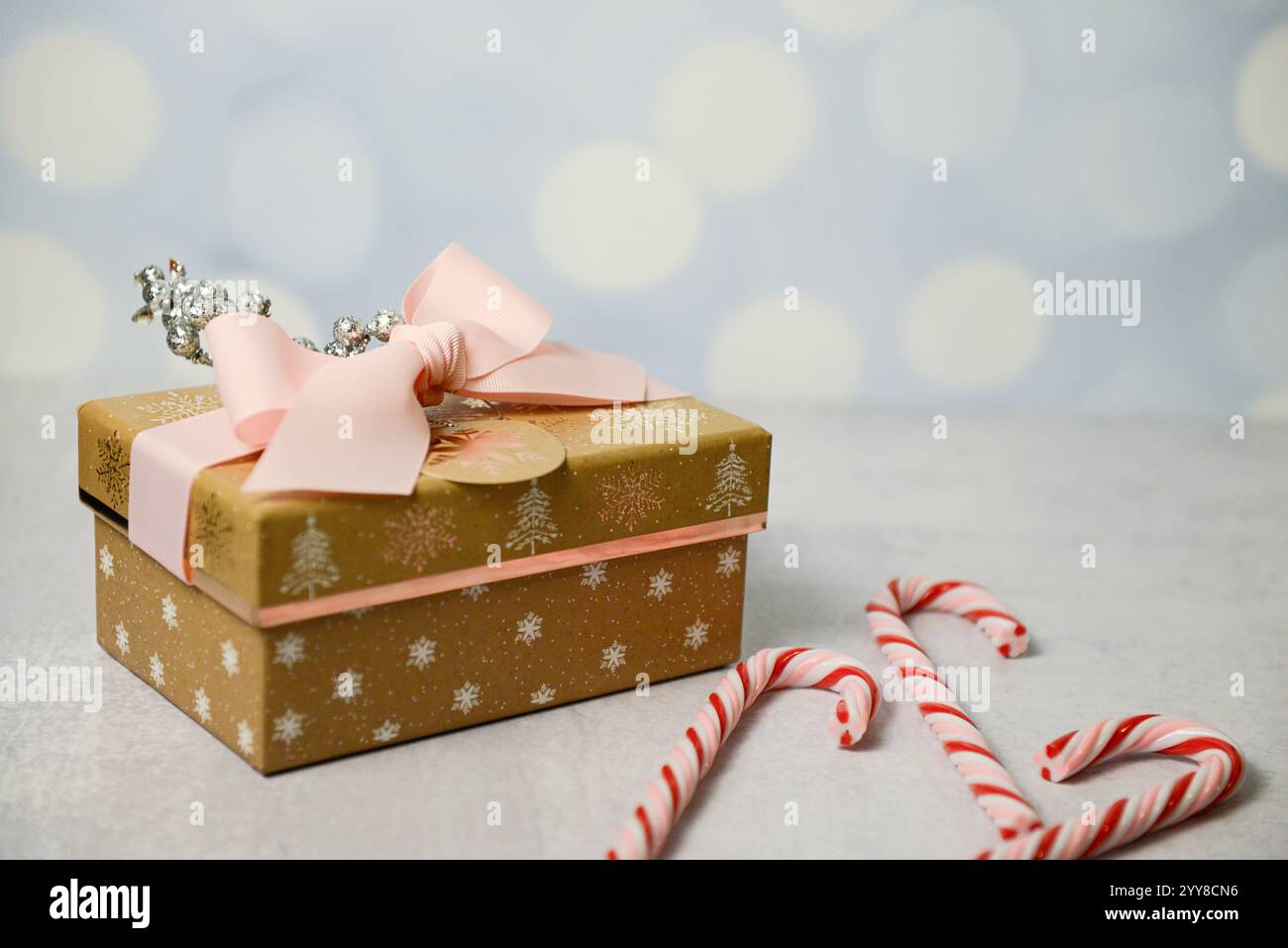 Cadeau doré festif avec ruban rose, décor de paillettes et canette de bonbons Banque D'Images