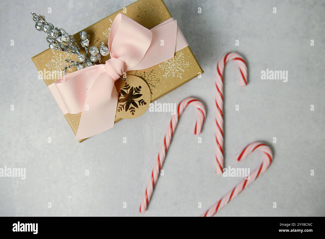 Cadeau festif avec ruban rose, étiquette de flocon de neige et cannes de bonbon. Banque D'Images