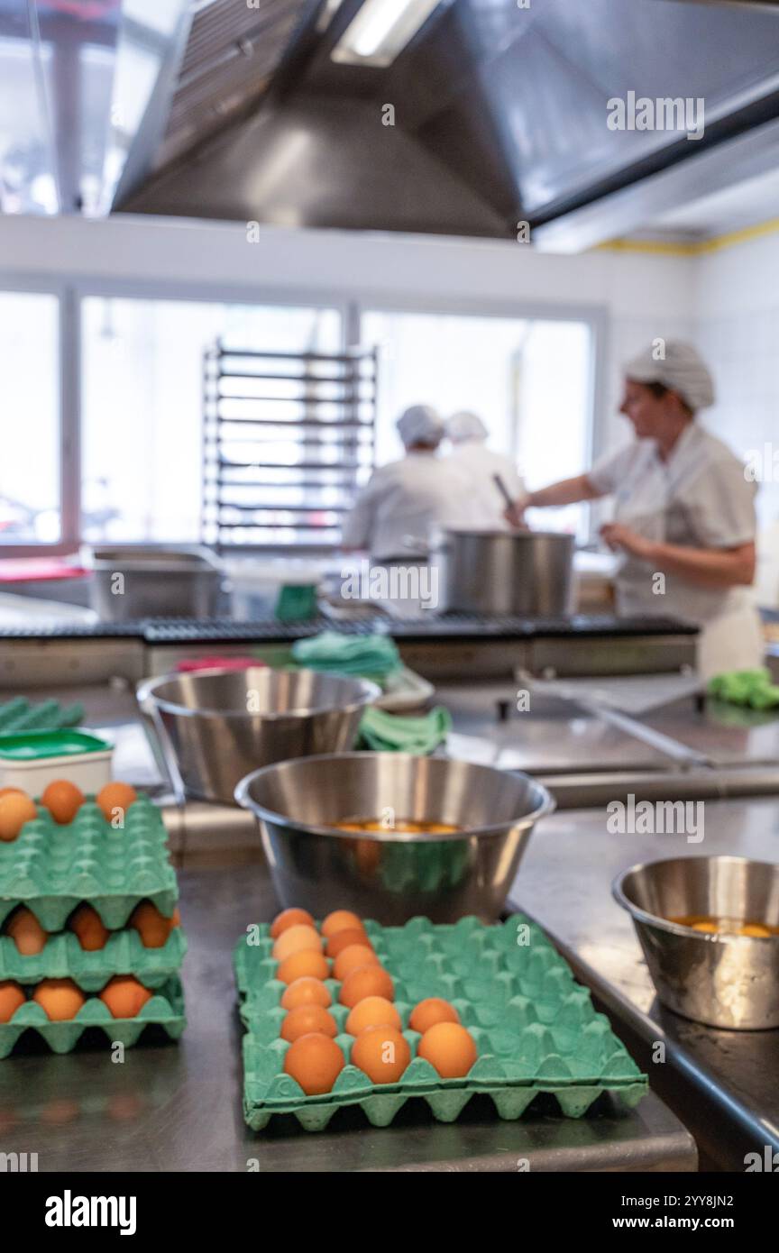 Restauration institutionnelle : cuisine dans un collège. Préparation des desserts, personnel de cuisine préparant les plats, oeufs pour les omelettes *** local Caption *** Banque D'Images