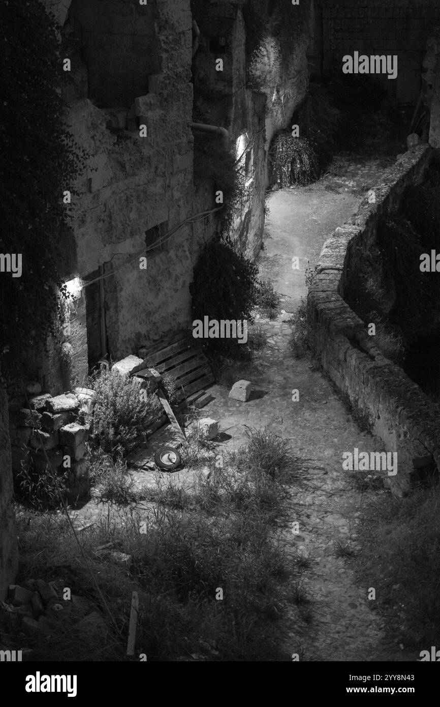 Vue nocturne d'une ancienne ruelle à Matera, en Italie, avec des murs de pierre et un éclairage spectaculaire Banque D'Images