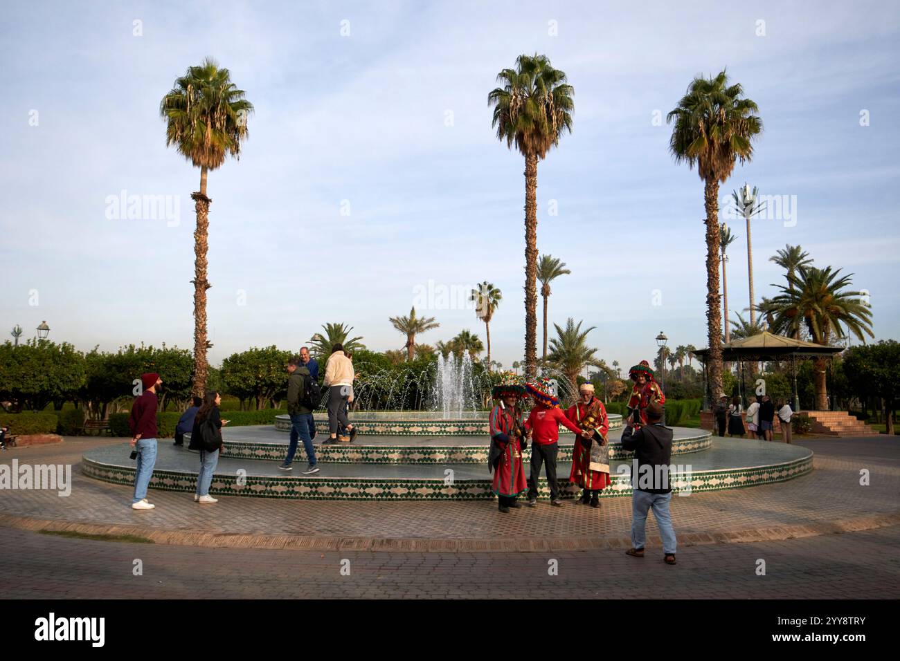 touristes et porteurs d'eau à une fontaine dans le parc lalla hasna parc koutoubia jardins marrakech, maroc Banque D'Images