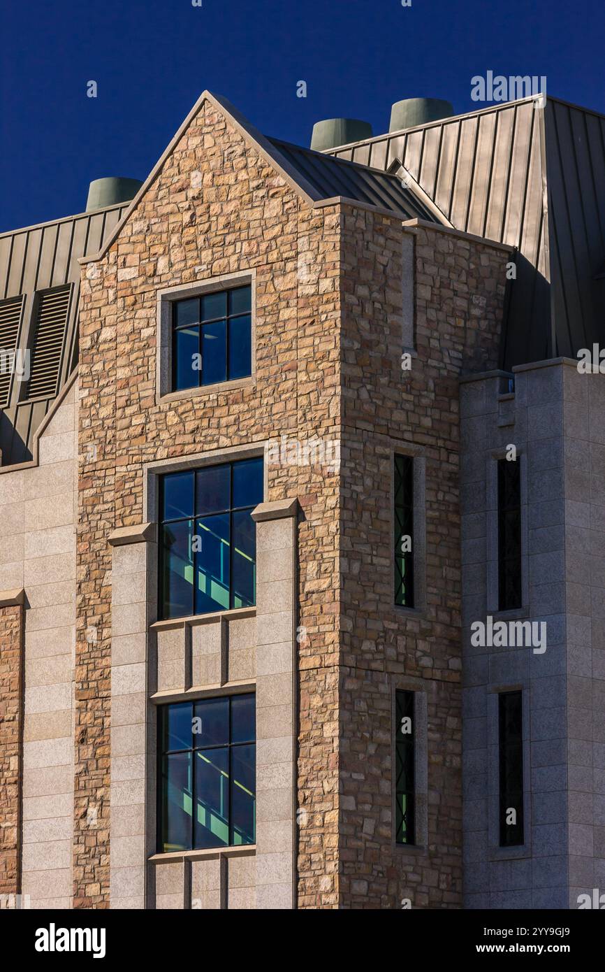 Un bâtiment avec une façade en pierre et un toit pointu. Le bâtiment a beaucoup de fenêtres, et le toit est recouvert de métal Banque D'Images