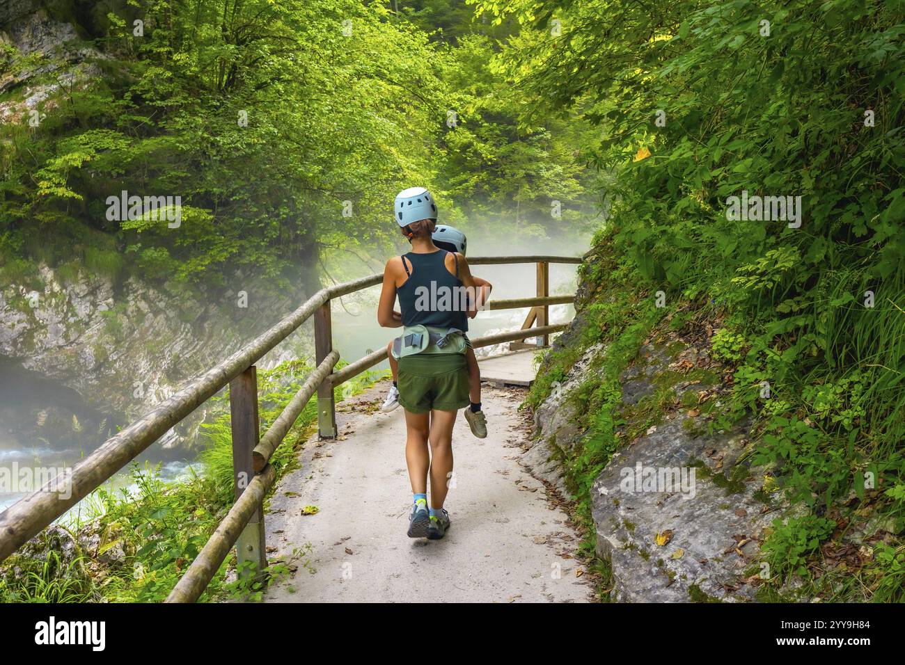 Mère portant son enfant lors d'une randonnée lors d'une journée d'été brumeuse dans la gorge de vintgar près de Bled, slovénie, profitant d'une promenade pittoresque à travers la nature Banque D'Images