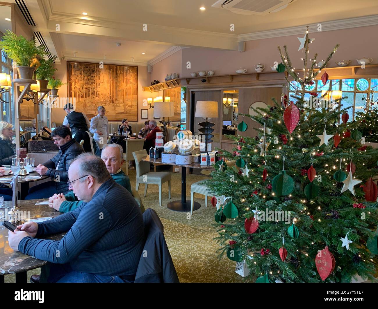 Magasin de thé Betty à Ilkley Yorkshire Angleterre nourriture manger l'après-midi tasse de thé soucoupe crème scones petits pains gâteaux serveuse à l'intérieur du stand magasin personne - Image de stock capturée avec un smartphone