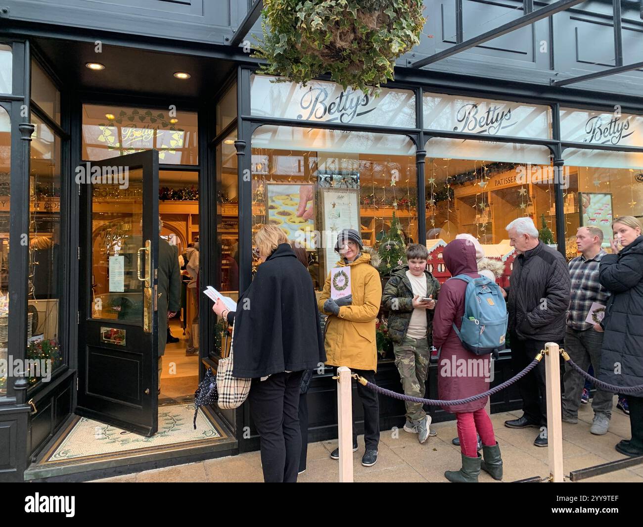 Magasin de thé Betty à Ilkley Yorkshire Angleterre nourriture manger l'après-midi tasse de thé soucoupe crème scones petits pains gâteaux serveuse à l'intérieur du stand magasin personne - Image de stock capturée avec un smartphone