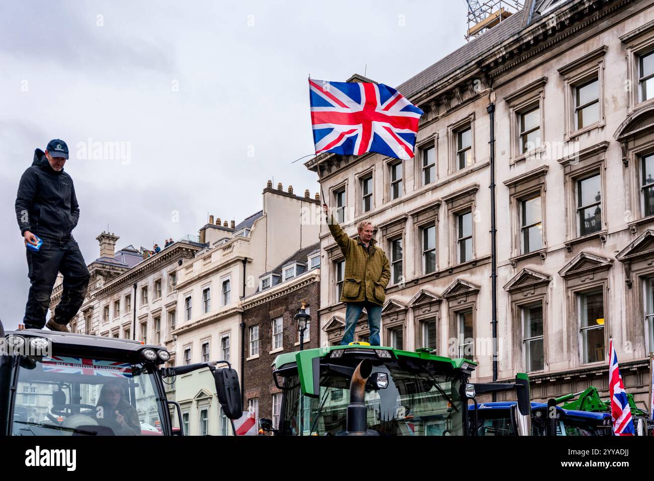 Les agriculteurs en colère contre les nouveaux changements apportés par le gouvernement à l'impôt sur les successions manifestent et agitent Un drapeau syndical depuis on Top of A Tractor à Whitehall , Londres, Royaume-Uni. Banque D'Images