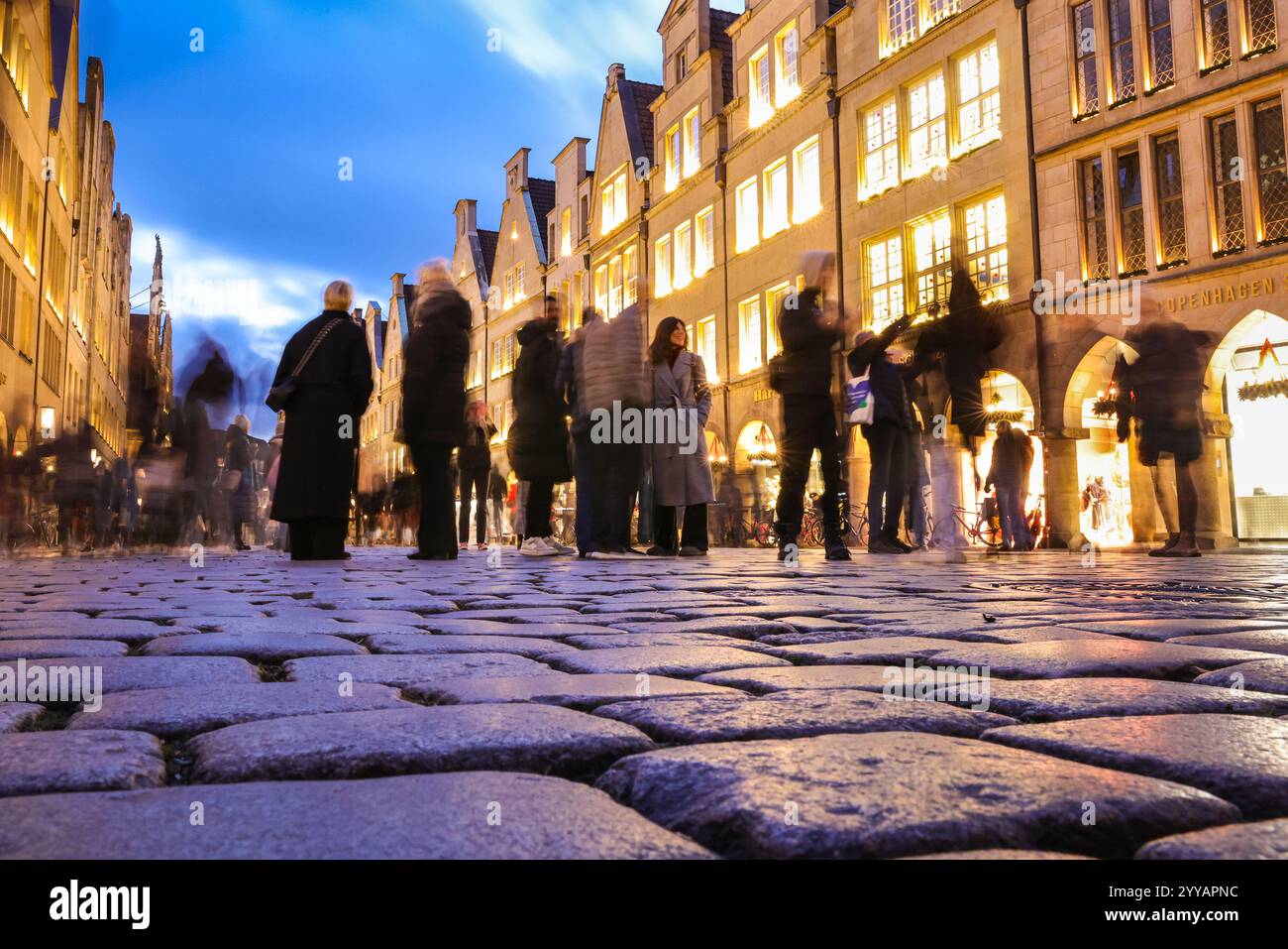 Münster, NRW, Allemagne, 20 décembre 2024. Le célèbre boulevard Prinzipalmarkt est fermé à la circulation et très fréquenté par les visiteurs. Münster (Muenster) et ses cinq marchés de Noël sont animés par des foules de visiteurs festifs de toute la NRW, ainsi que des pays-Bas et d'ailleurs ce soir. Des milliers de personnes affluent vers les marchés traditionnels du pittoresque centre-ville historique. Une sécurité renforcée est visible, les voies d'accès sont limitées, les espaces entre les rues et les marchés ont été bloqués avec des sacs de sable en acier ou en béton et d'autres mesures. Ce soir, une attaque a été menée à Magdebourg Christmas Banque D'Images