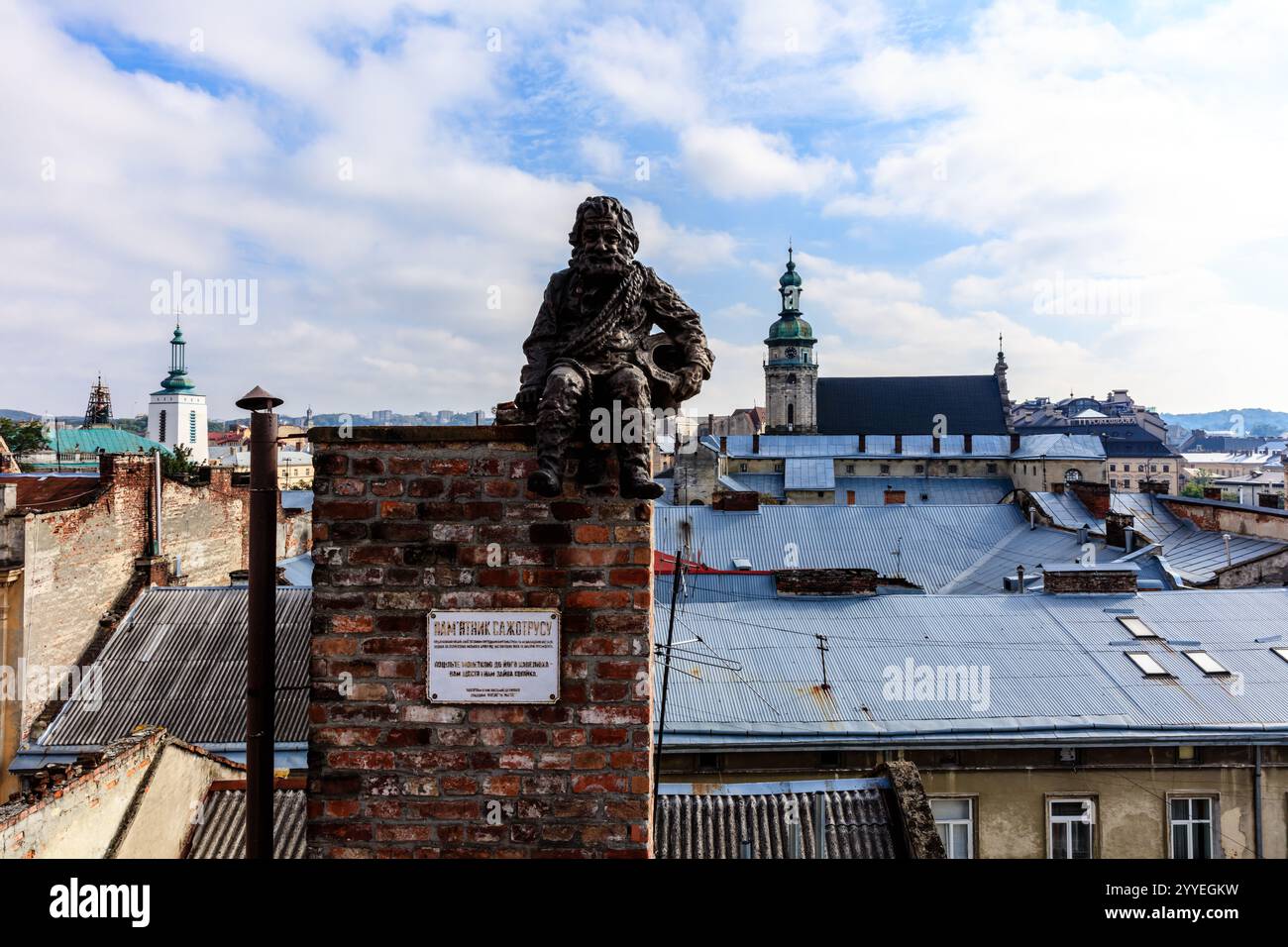 Une statue d'un homme est assise sur une cheminée en brique. La cheminée est sur le toit d'un bâtiment Banque D'Images