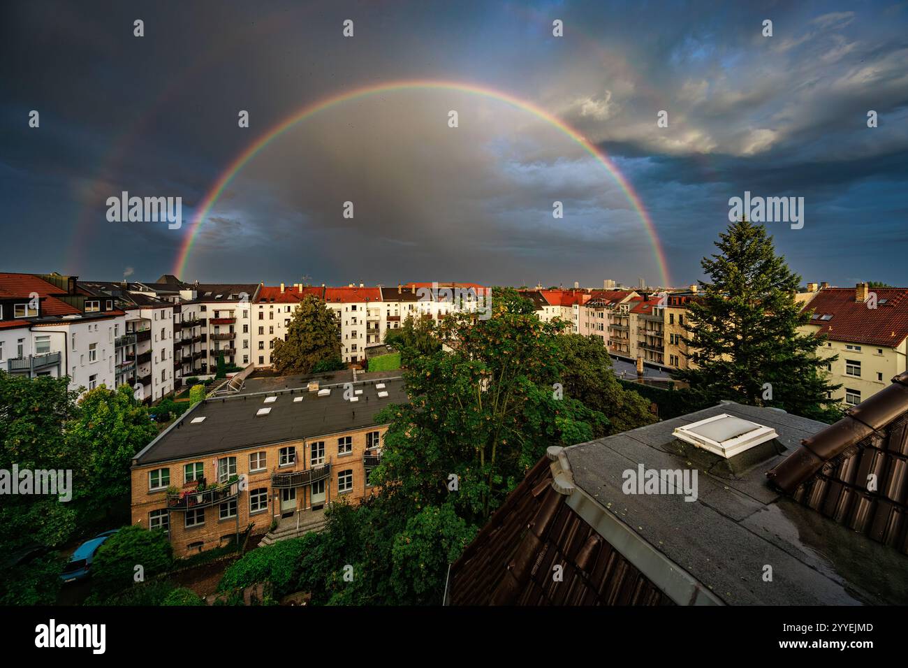 un double arc-en-ciel contre un ciel nuageux dramatique au-dessus de vieilles maisons de ville Banque D'Images