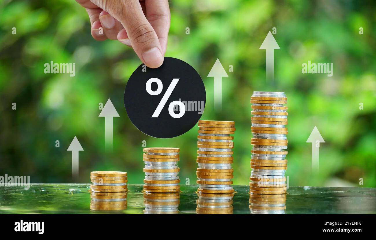 Main tenant des cartes avec des symboles de pourcentage au-dessus d'une pile de pièces. Concept de croissance et d'augmentation financières, d'investissement, de taux d'intérêt, d'impôts. Banque D'Images
