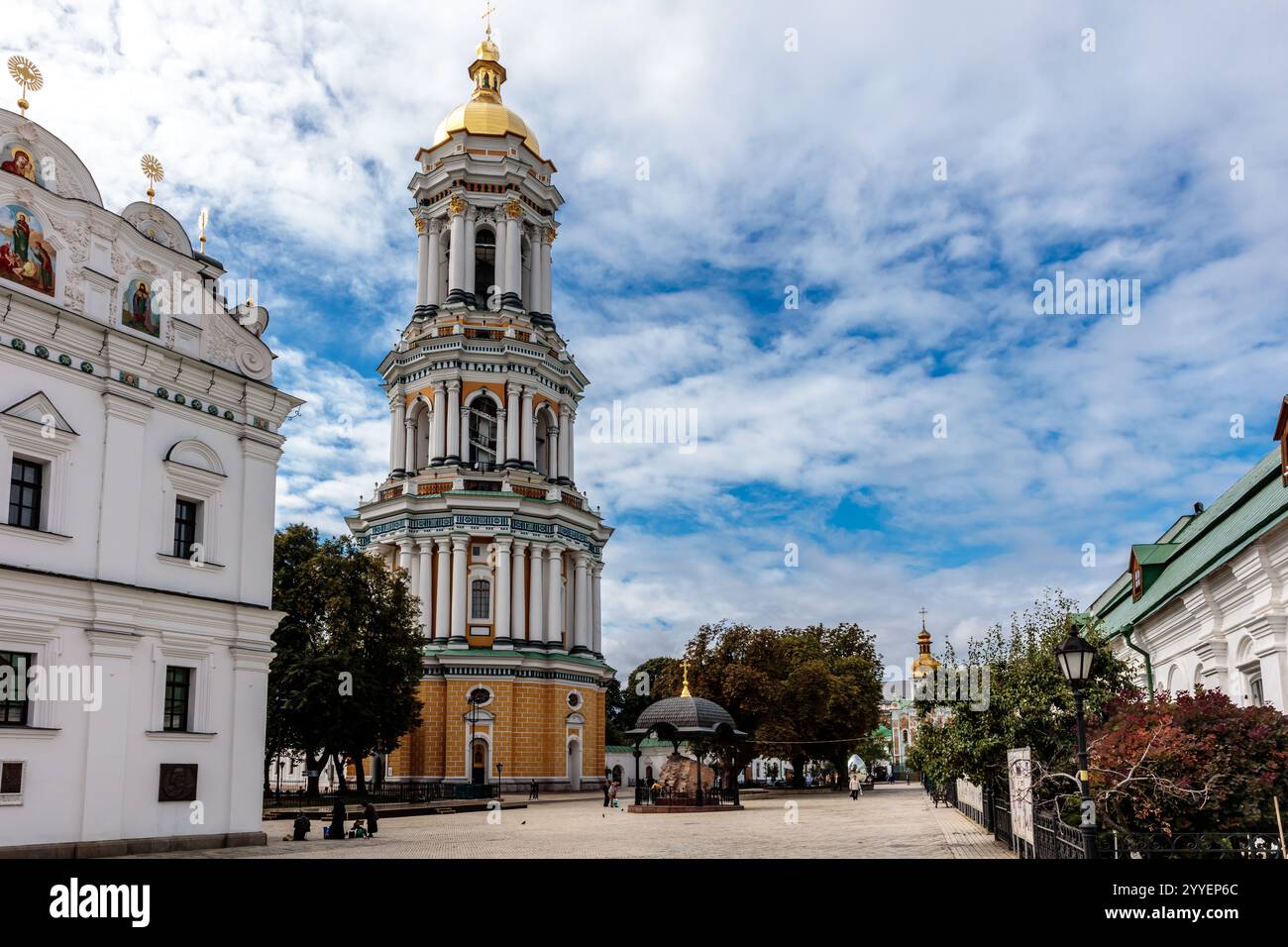Un grand bâtiment orné avec un dôme doré se trouve devant un bâtiment blanc. Le ciel est bleu et il y a quelques personnes qui marchent autour de la zone Banque D'Images