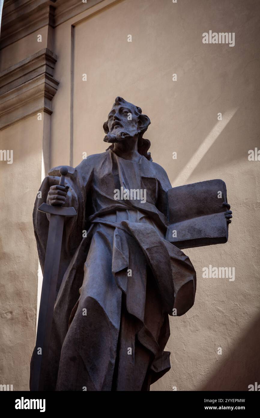 Statue d'un homme tenant une épée et un livre. La statue est d'une figure religieuse et est faite de pierre Banque D'Images