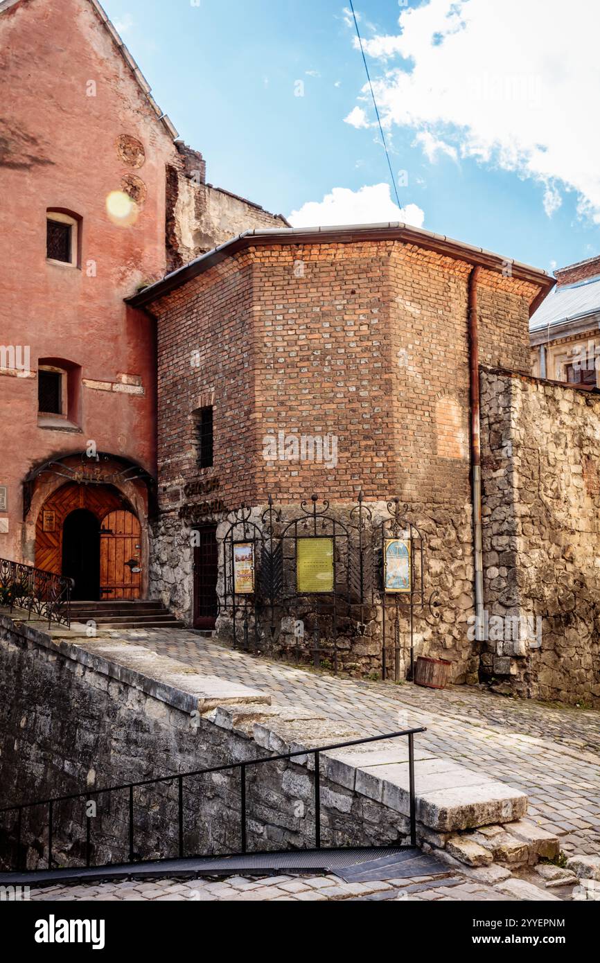 Un bâtiment en briques avec un toit rouge et un escalier en pierre qui y mène. Le bâtiment a une petite cour avec quelques panneaux sur l'affichage Banque D'Images