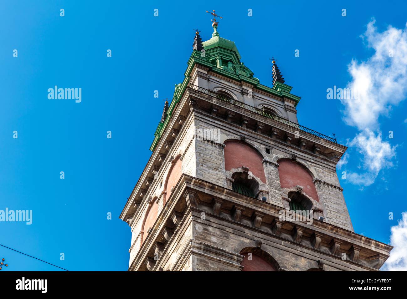 Un grand bâtiment avec un toit vert et une croix sur le dessus. Le ciel est bleu et il y a quelques nuages Banque D'Images