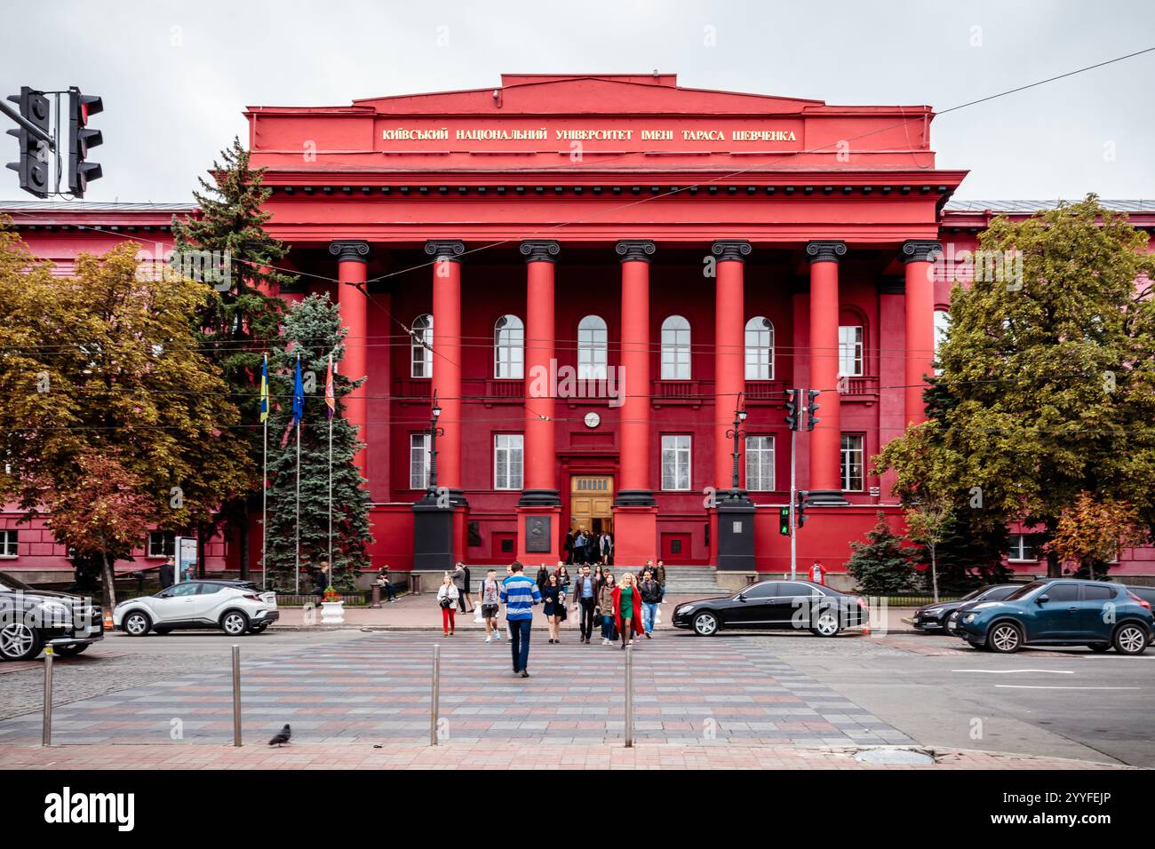 Un bâtiment rouge avec un grand panneau sur le devant. Le bâtiment est entouré de voitures et de gens Banque D'Images