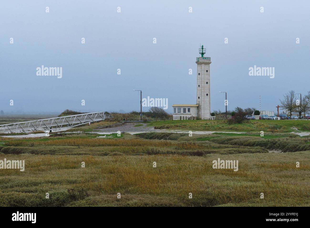 Phare unique se dresse au milieu d'un paysage côtier tranquille avec un ciel couvert et des marais environnants à l'aube Banque D'Images