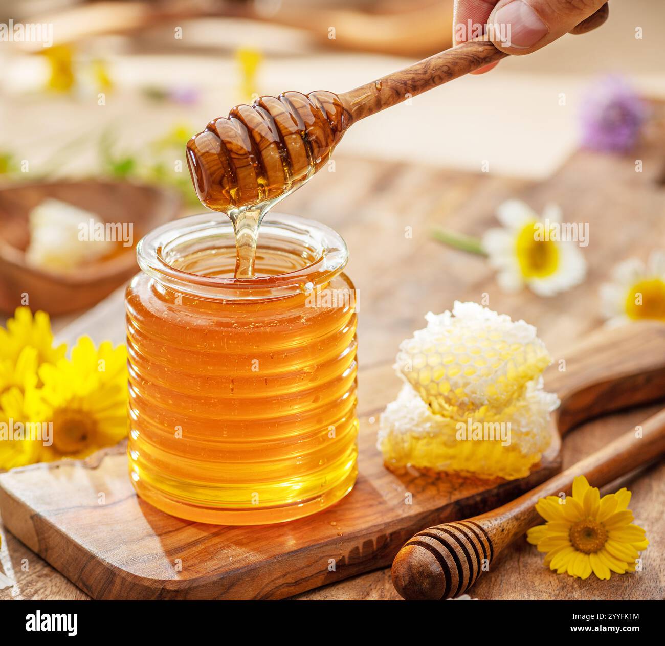 Miel biologique naturel dans le pot en verre, la trempette de miel et les nids d'abeilles sont à proximité. Fond alimentaire naturel. Banque D'Images