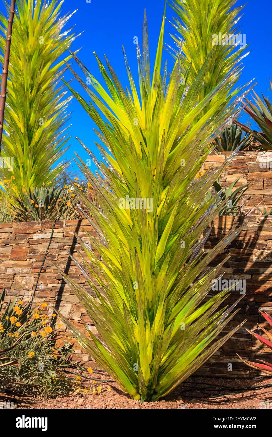 Une grande plante verte avec une longue tige et des feuilles. La plante est entourée d'un mur de briques Banque D'Images