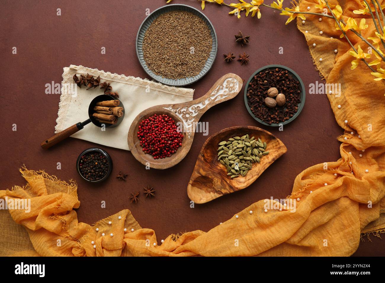 Une collection d'herbes et d'épices pour la cuisine asiatique, sur un fond brun avec un tissu jaune safran à encadrer. Banque D'Images