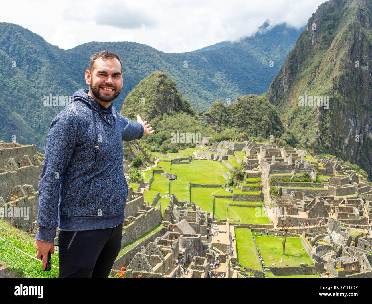 Un heureux voyageur barbu pointant vers Machu Picchu se demande dans une journée ensoleillée Banque D'Images