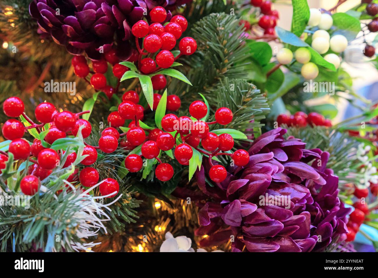 Baies de Noël rouges et fleurs violettes sur le sapin de Noël. Décoration de Noël fleurie aux baies. Banque D'Images