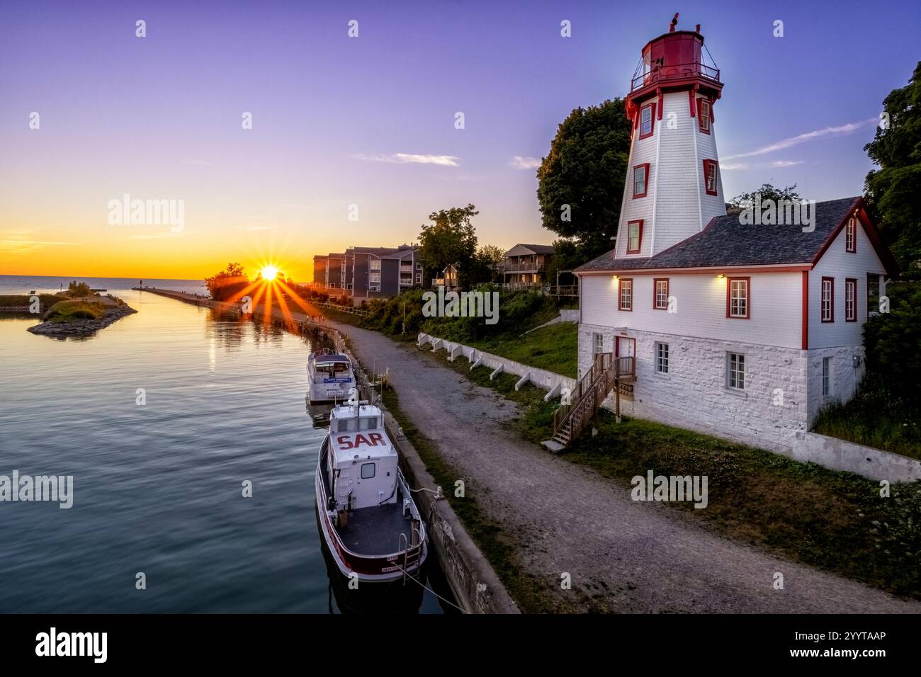 Port de Kincardine au coucher du soleil, avec le phare emblématique sur la rive du lac Huron. Une scène sereine mettant en valeur la beauté côtière de l'Ontario. Banque D'Images