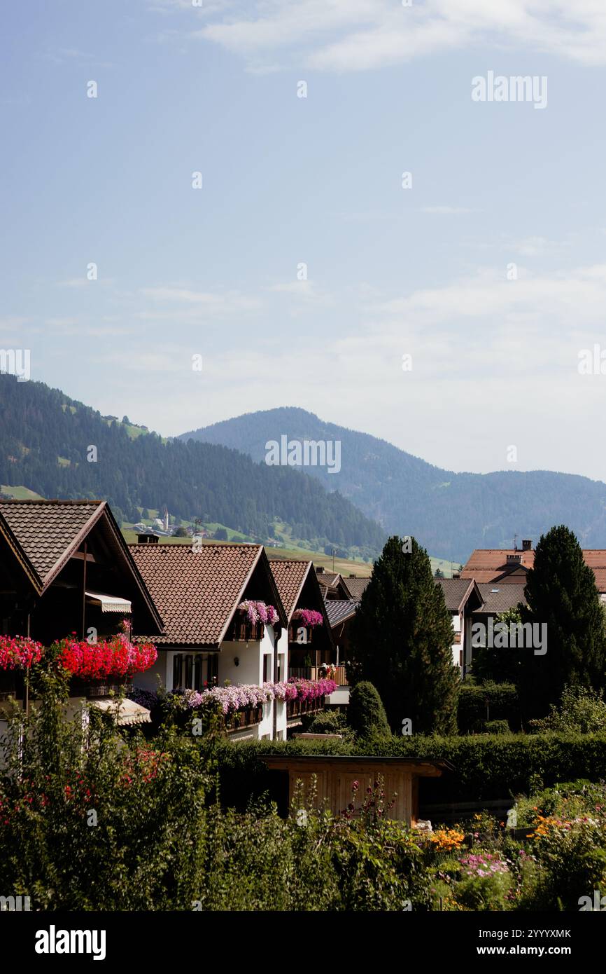 Chalets alpins traditionnels avec des jardinières sur les balcons, nichés contre des montagnes vertes sous un ciel bleu Banque D'Images