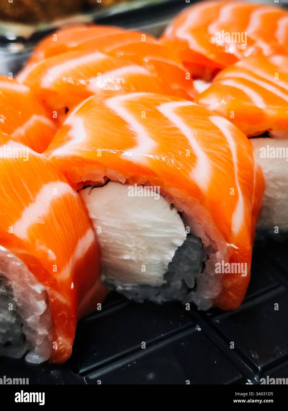 Un gros plan de rouleaux de sushi au saumon fraîchement préparés, mettant en valeur la couleur orange vibrante du poisson et la texture délicate du riz. Banque D'Images