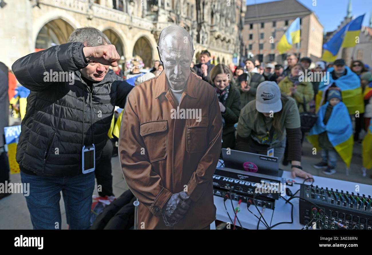 Munich, Allemagne. 02 mars 2025. Un participant au rassemblement "L'Europe se tient ensemble - montre la force pour la paix et la liberté" sur Marienplatz gestes à côté d'une figure en carton du président russe Poutine vêtue de menottes et de vêtements de prison. Le rassemblement a eu lieu en partie en raison de la visite du chef de l’État ukrainien Selenskyj au président américain Trump à la Maison Blanche. Crédit : Uwe Lein/dpa/Alamy Live News Banque D'Images