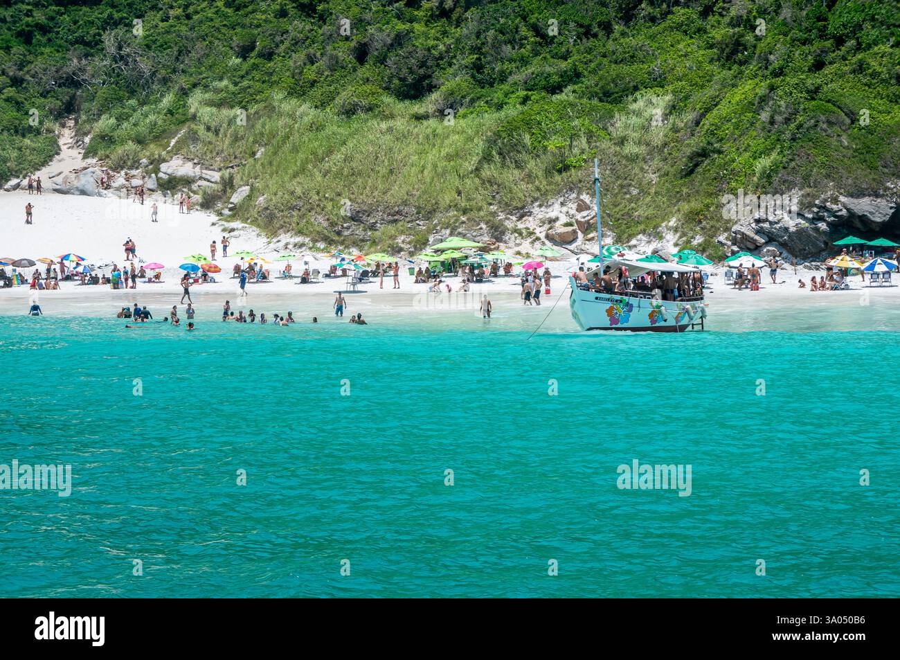 Bateau Xarelete IV ancré près des amateurs de plage à Pontal do Atalaia Beach côté nord sur les eaux de la baie Guriri Cove sous une chaude journée d'été après-midi. Banque D'Images