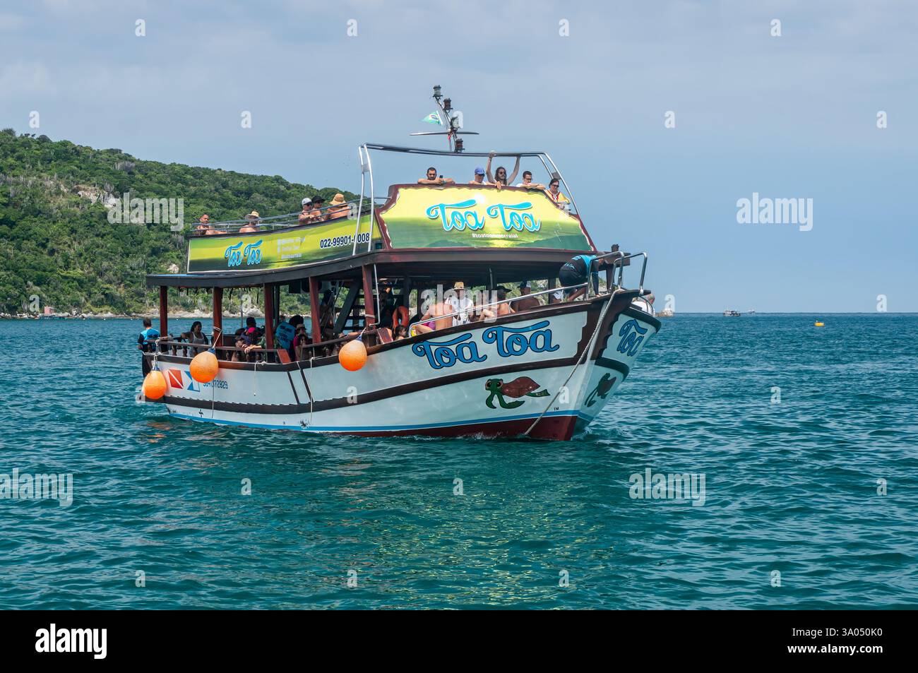 Toa Toa voilier arrivant plein de touristes à Forno Cove Bay eaux bleues entourées de collines verdoyantes denses sous ciel nuageux ensoleillé d'été. Banque D'Images Toa Toa voilier arrivant plein de touristes à Forno Cove Bay eaux bleues entourées de collines verdoyantes denses sous ciel nuageux ensoleillé d'été. Banque D'Images