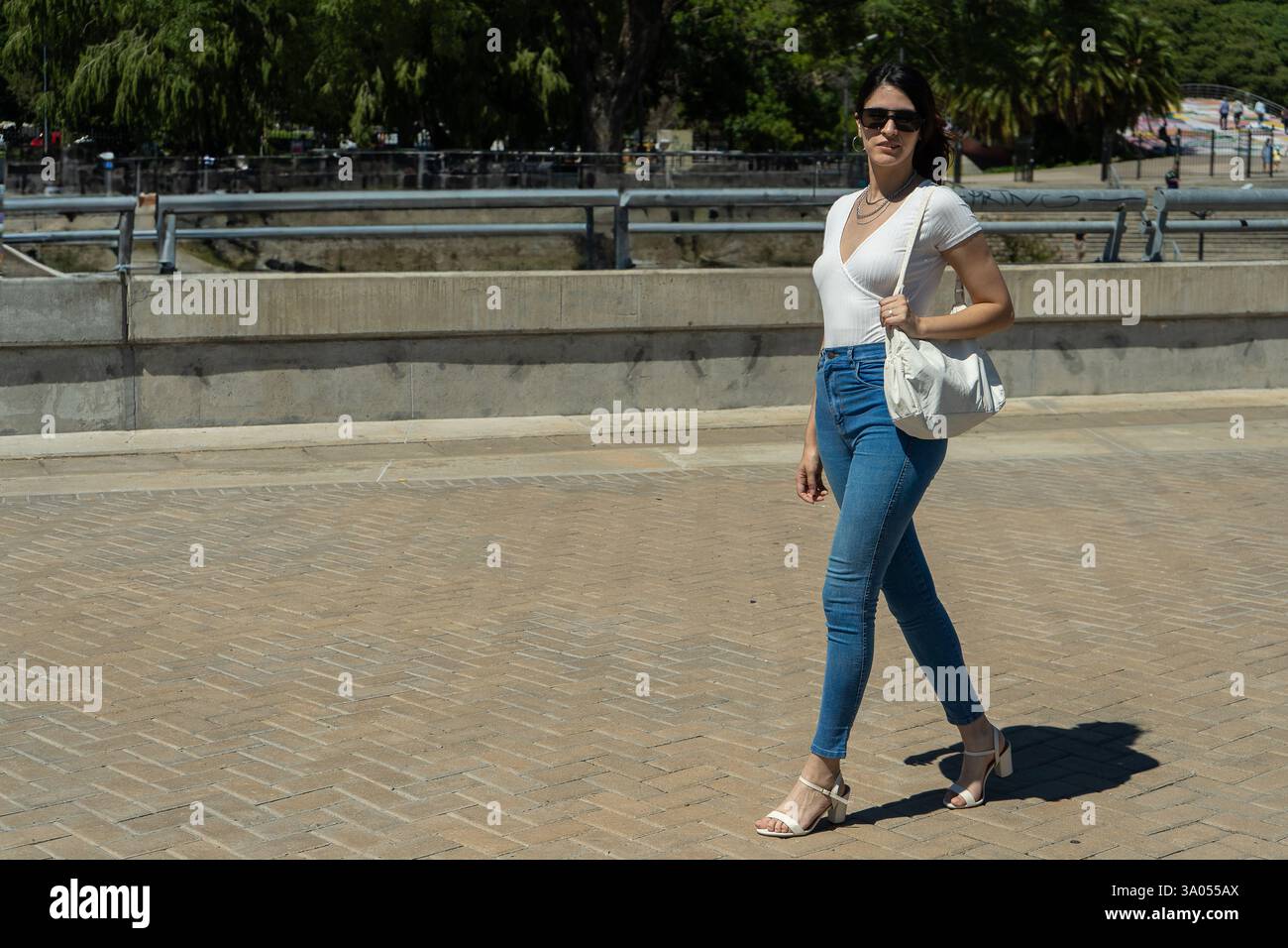 Jeune femme latine élégante marchant en toute confiance sur un trottoir de la ville par une journée ensoleillée Banque D'Images