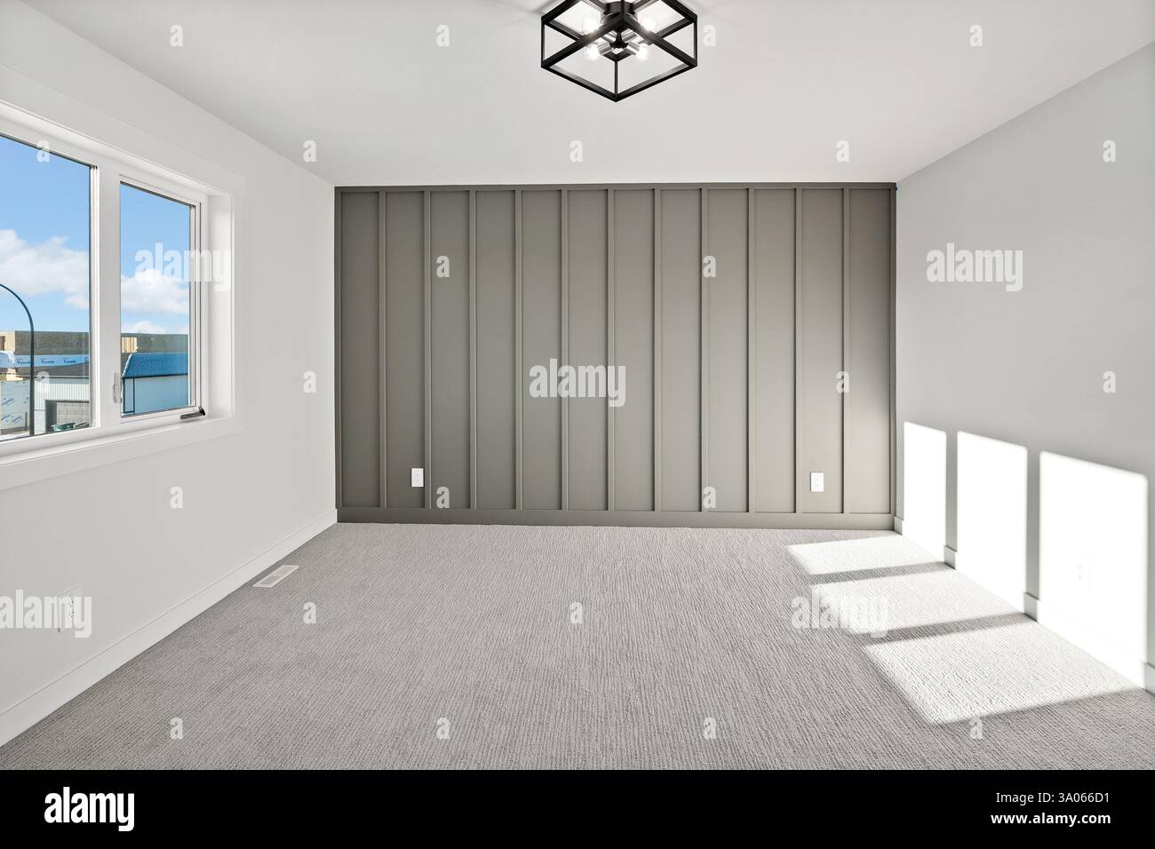 Grande chambre avec un mur gris et une fenêtre. La chambre est vide et a un look épuré et minimaliste Banque D'Images