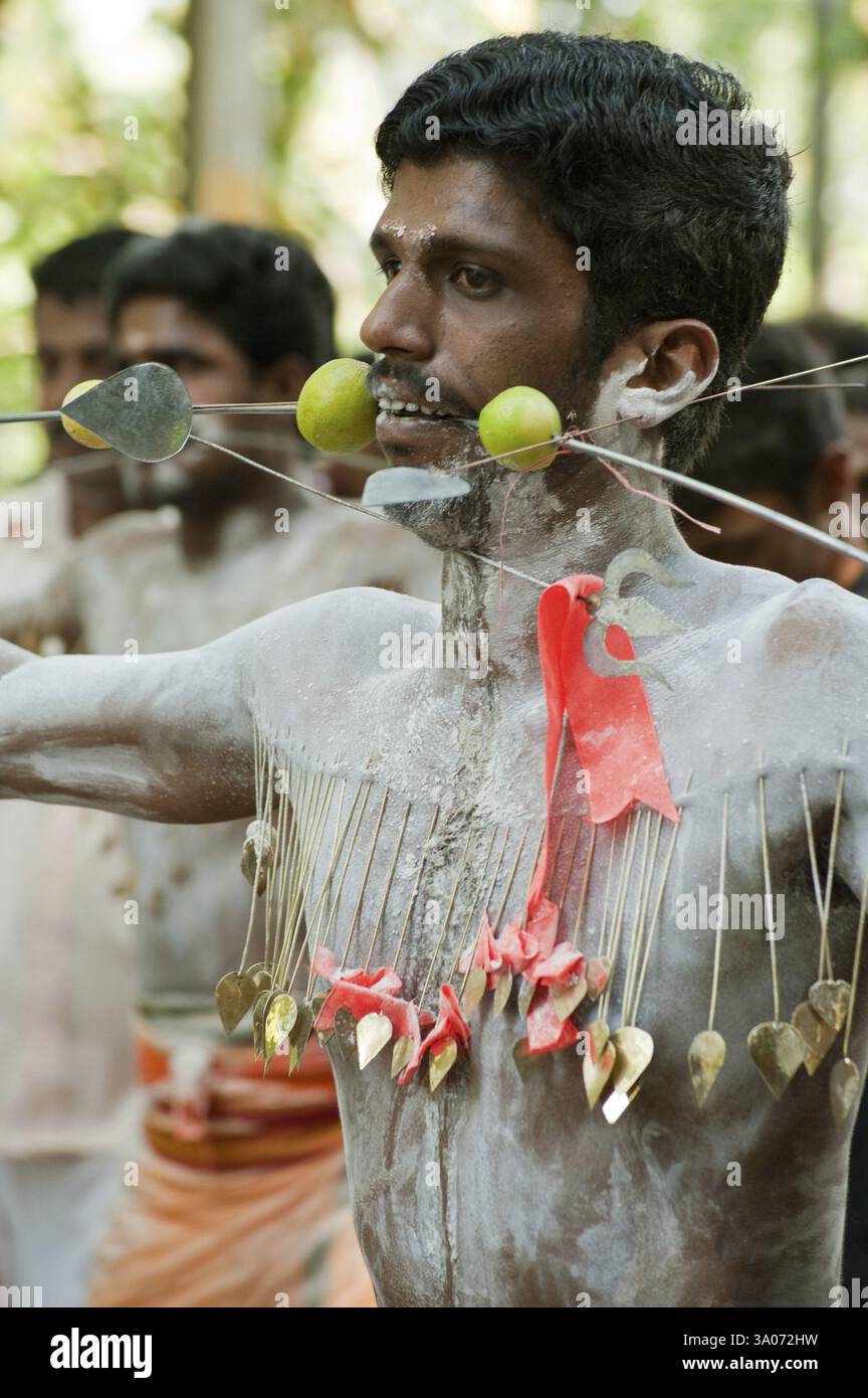 Homme perçant la pointe à travers les joues déchargeant le vœu au festival de Thaipusam, Kerala, Inde NOMR Banque D'Images