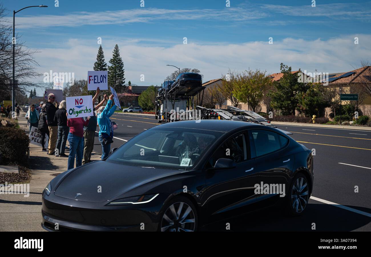 Les manifestants brandissent des pancartes comme No oligarchs et F-Elon devant une toute nouvelle voiture noire Tesla qui a été déchargée et qui est conduite dans une concession Tesla. Banque D'Images