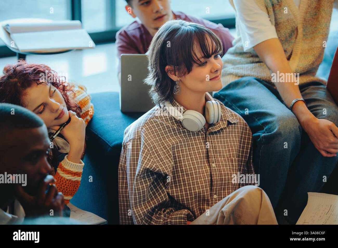 Un groupe d'étudiants écoutant attentivement pendant une séance d'éducation, reflétant l'apprentissage collaboratif et l'engagement actif dans un milieu universitaire diversifié Banque D'Images