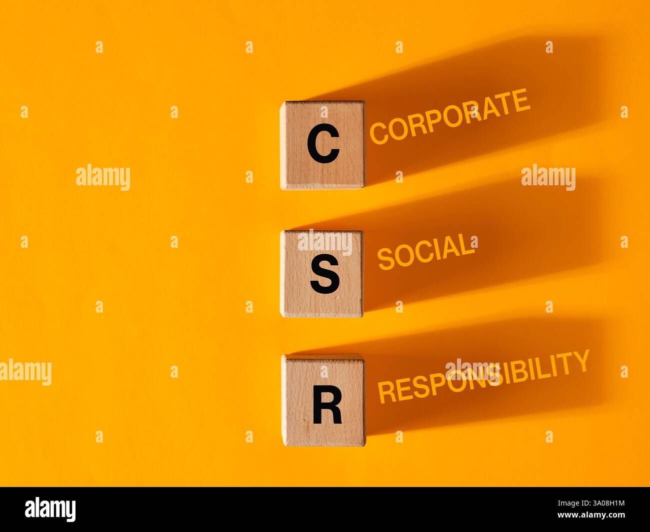 Blocs en bois avec l'acronyme CSR, représentant la responsabilité sociale des entreprises sur fond jaune. Banque D'Images