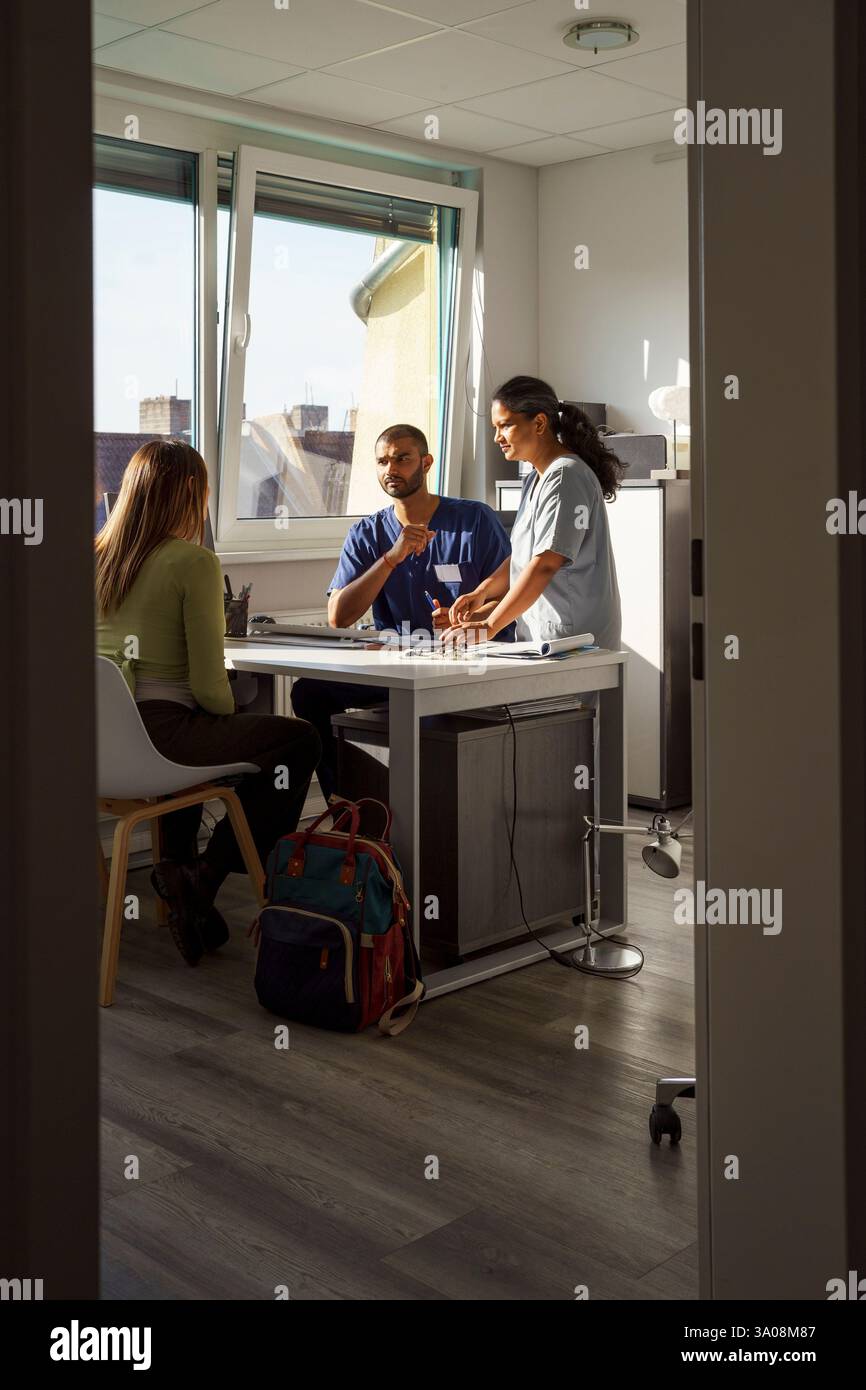 Professionnels de la santé masculins et féminins parlant avec le patient dans le cabinet du médecin à l'hôpital Banque D'Images